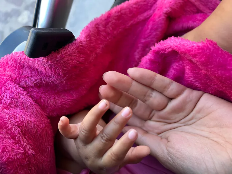 A mother's hands holding her baby's hand