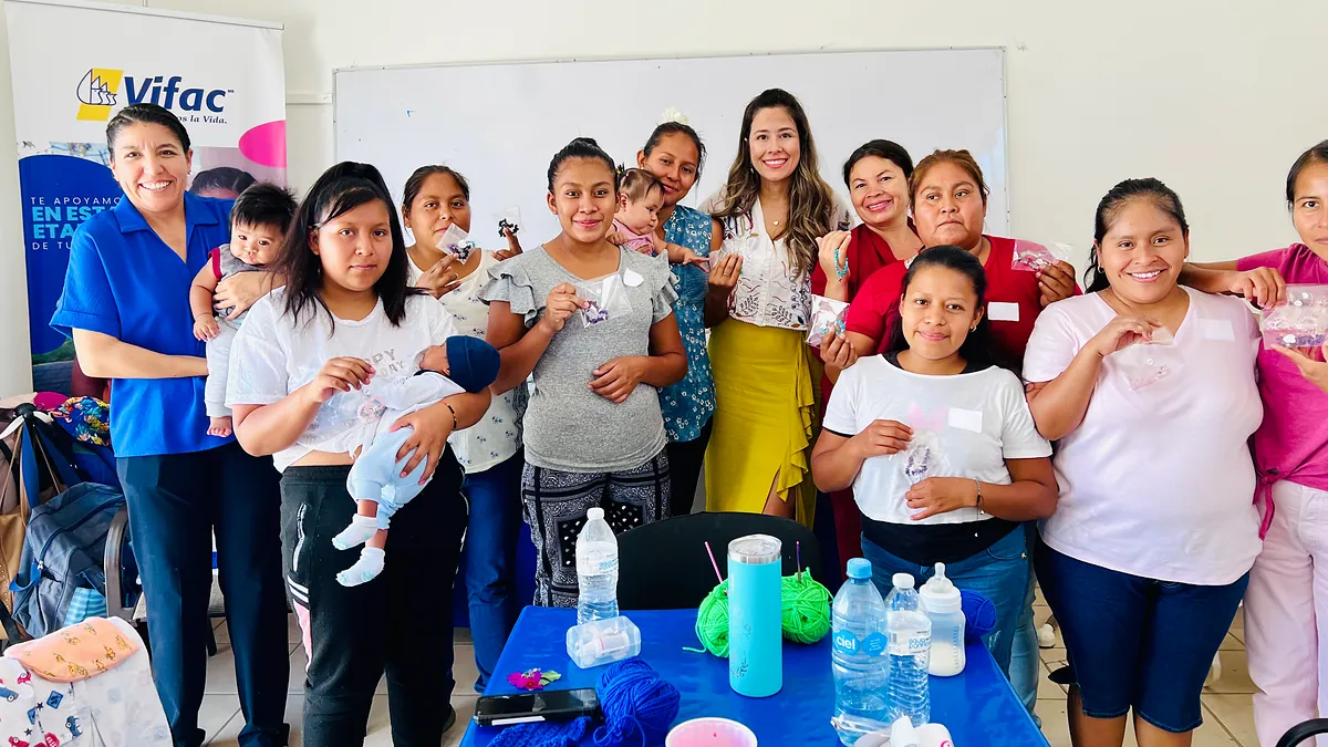 A member of the What's in Cabo family, center in white, with VIFAC Los Cabos moms holding up the bracelets they made at the workshop; some hold their babies