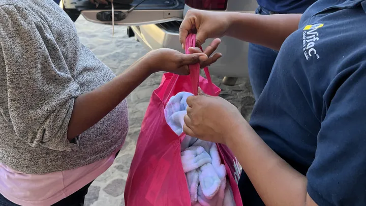 A VIFAC Los Cabos team member hands a support bag to a mom