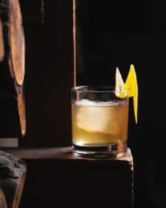 A house cocktail on the wood bar beside the firewood at Carbón Cabrón