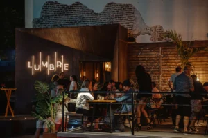 Diners under the Lumbre neon sign on the brick wall