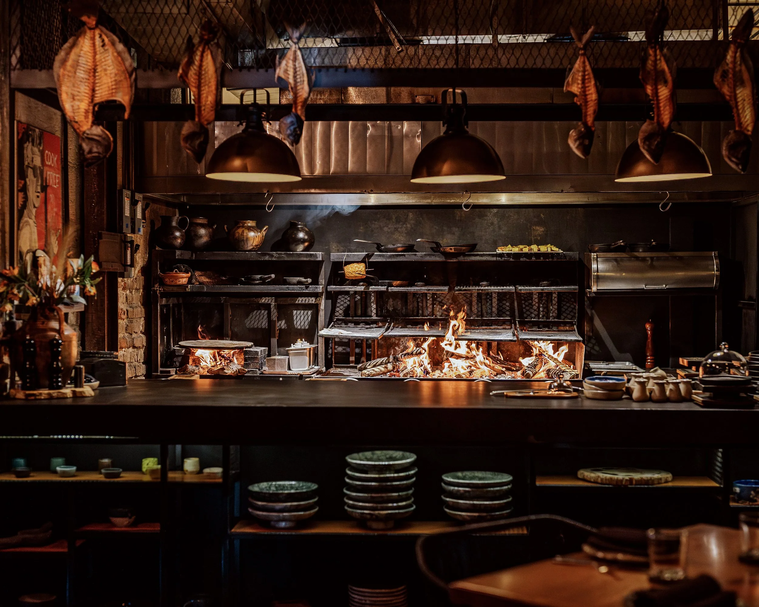 The open kitchen at Lumbre, with the fire lit under the hanging lamps