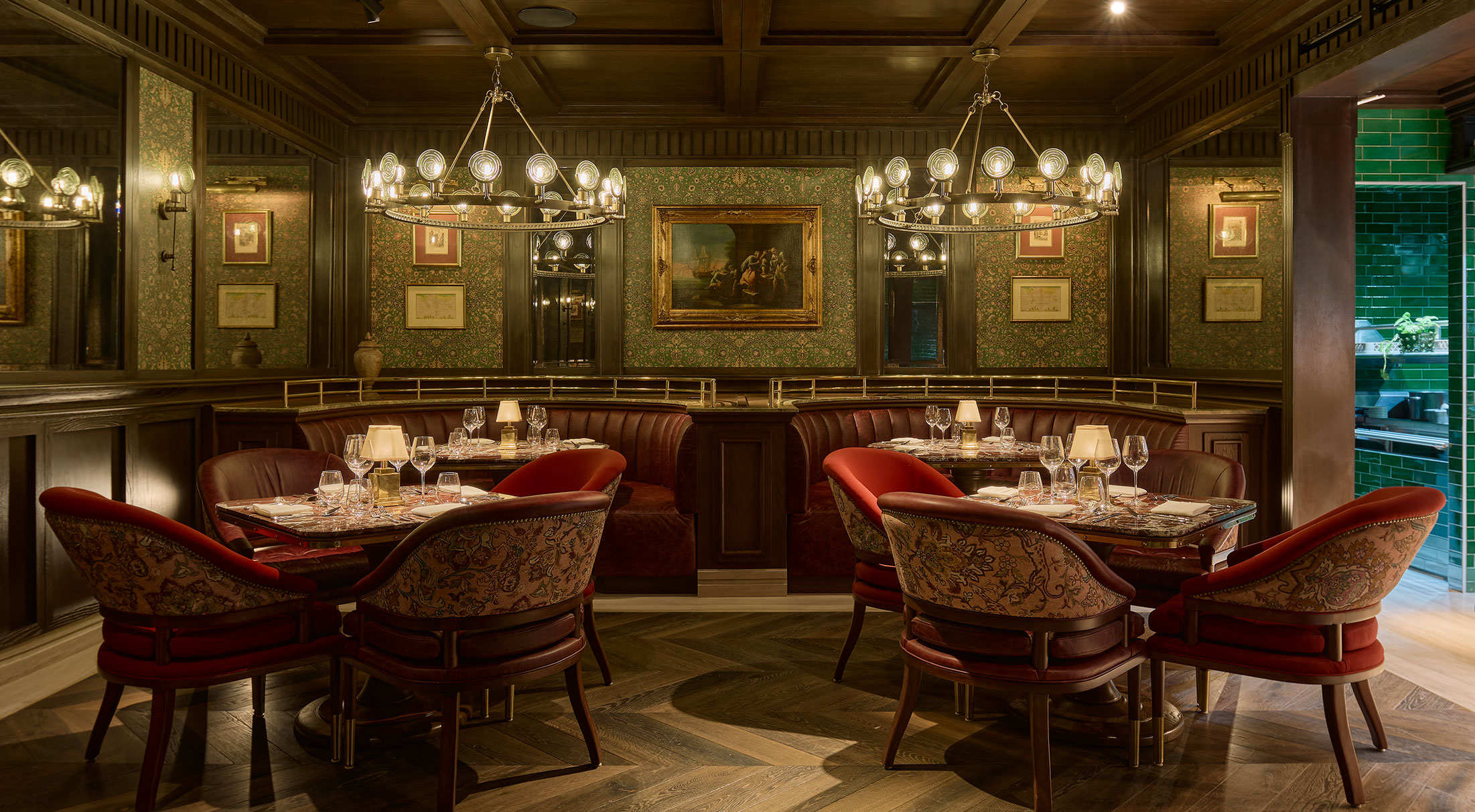 Main dining room with wood paneling, chandeliers, curved leather banquette and red club chairs