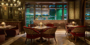 Dining room view toward the signature jade-green tiled open kitchen with red velvet chairs