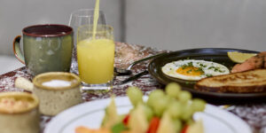 Close-up breakfast plating with fried egg, toast, fresh juice and fruit