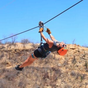 Zipliner crossing the desert canyon under blue skies at Wild Canyon, Los Cabos