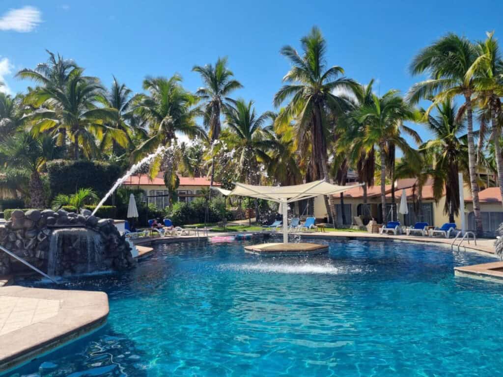 Buena Vista Oceanfront & Hot Springs Resort — free-form pool with a rock waterfall and loungers under the palms