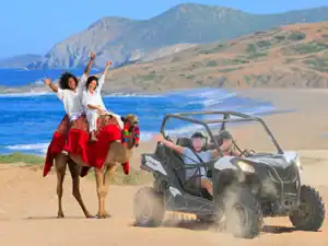 Camel riders and RZR vehicle at Migriño Beach in Los Cabos
