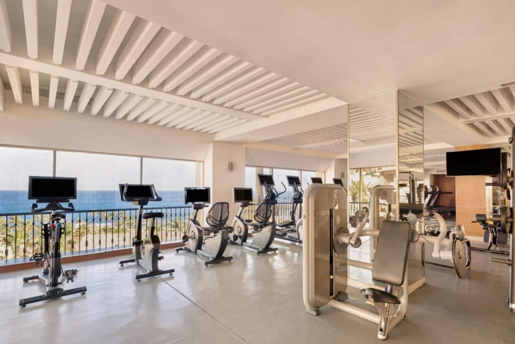 Grand Fiesta Americana Los Cabos Golf & Spa Resort — gym with exercise bikes and machines facing floor-to-ceiling sea views