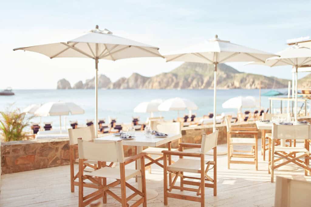 Tables and white umbrellas overlooking the bay at SUR Beach House