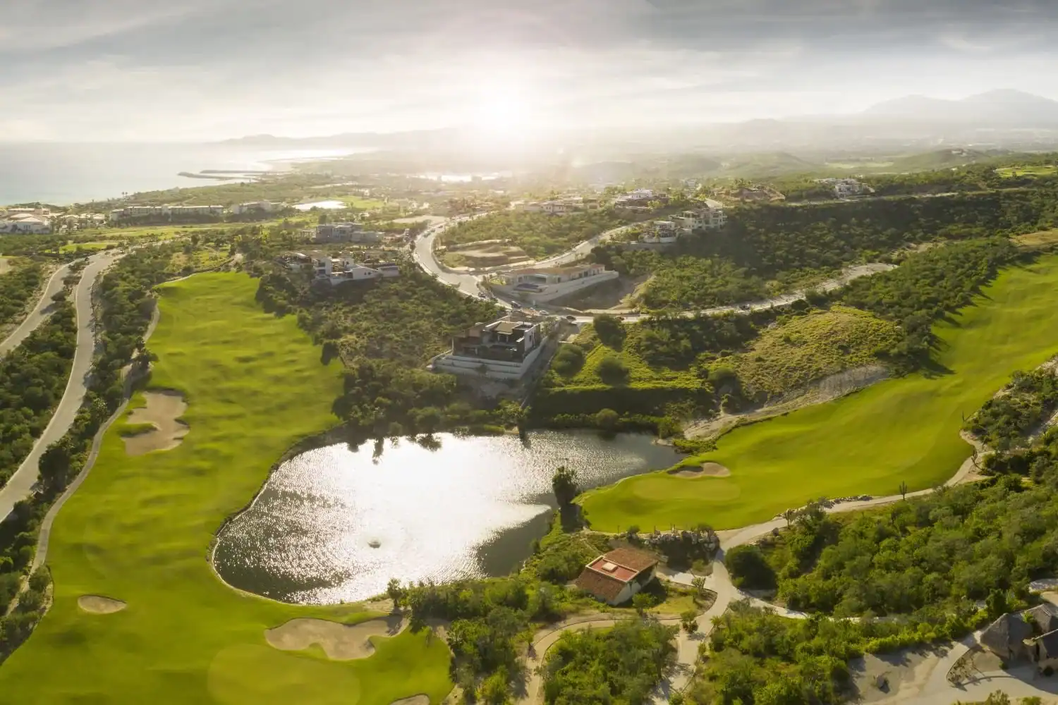 Vista fairways descending around a lake with the Sea of Cortez beyond