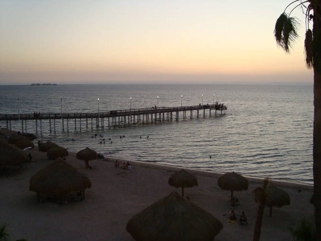 Palapas and the pier at Playa El Coromuel in La Paz