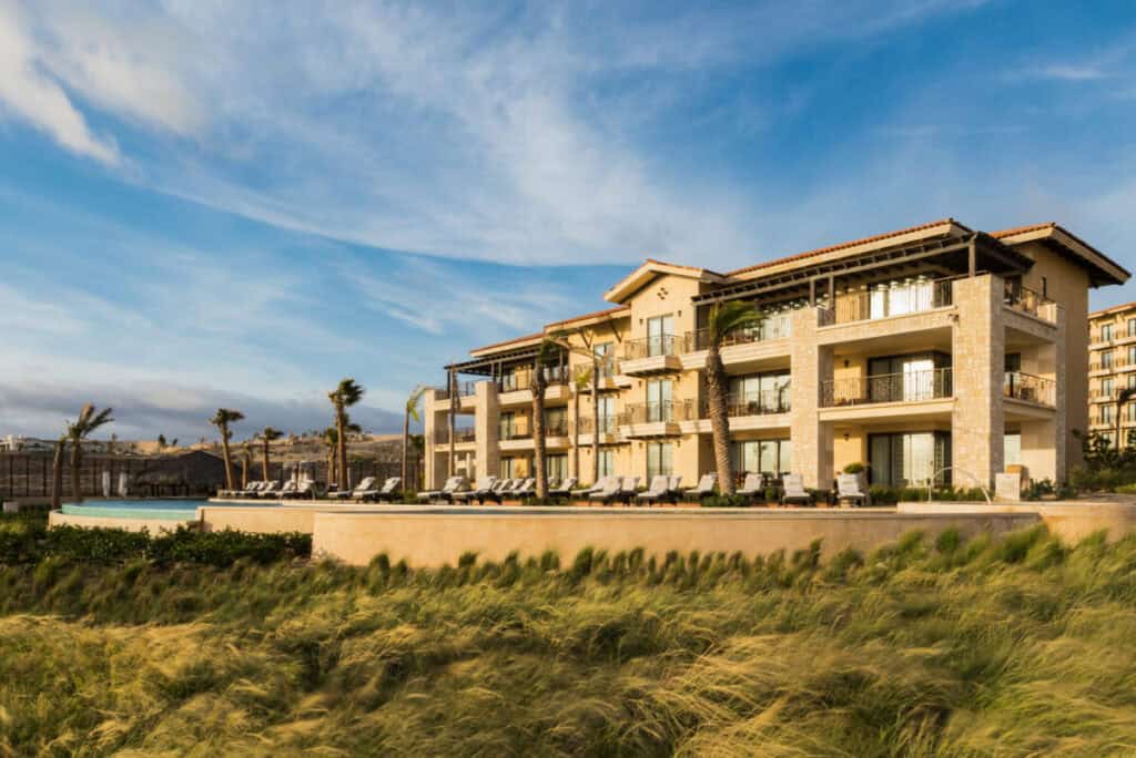 Grand Solmar The Residences — stone and timber residences above the dune grass, with the pool below