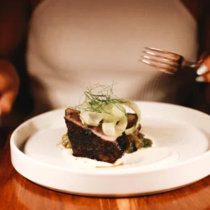 Plated grilled short rib with shaved fennel and labneh at Bar Esquina, Cabo San Lucas