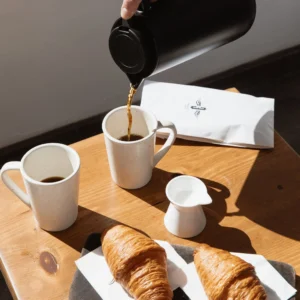 Coffee being poured into a ceramic mug beside croissants at the Bar Esquina coffee shop, Cabo San Lucas