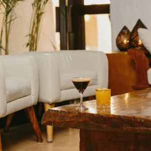 Lounge corner with a cocktail and candle on a rustic wood table at Bar Esquina, Cabo San Lucas