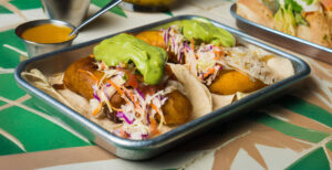 Baja fish tacos with slaw and avocado sauce on a metal tray
