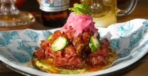 Tuna tostada topped with pickled onion and jalapeno