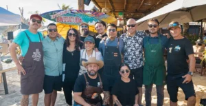 Barracuda Cantina staff gathered on the beach under the cantina sign