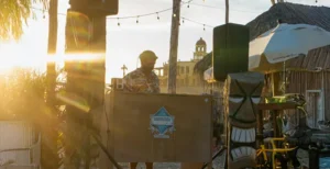 DJ spinning at sunset by the beach bar with tiki decor