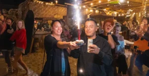 Guests celebrating with a sparkler dessert amid a lively crowd