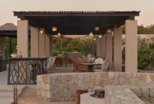 Pergola dining terrace at dusk with star lanterns and a stone firepit