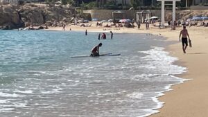Paddleboarder entering the water at Chileno Bay Public Beach