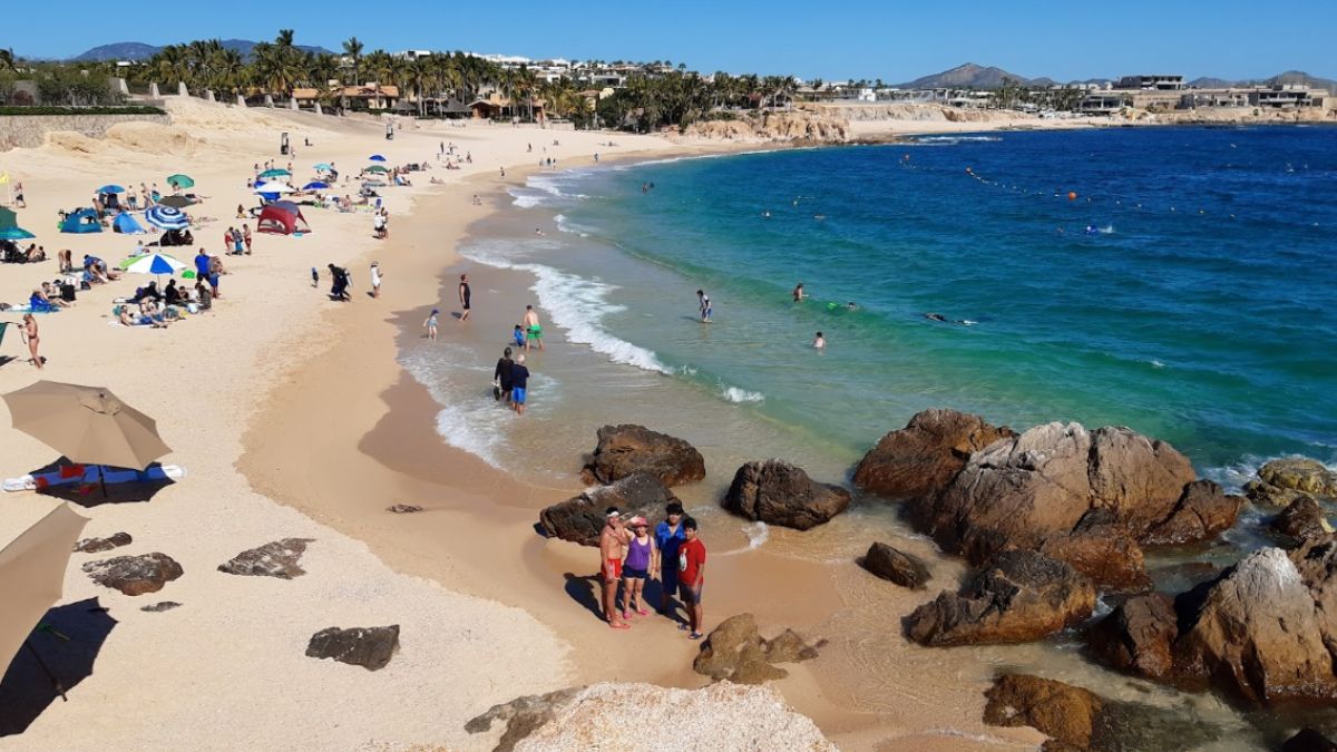 Wide view of Chileno Bay Public Beach with clear water and rocky shore