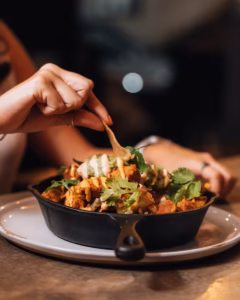 Cast-iron skillet of loaded nachos with cilantro, salsa, and drizzled sauces