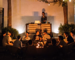 Nighttime courtyard gathering with a DJ and guests around a fire pit