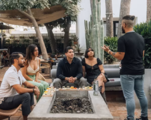 Guided mezcal tasting for guests seated around an outdoor fire pit with cacti