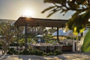 El Puesto palapa and its sign at sunset, seen from the sand at Four Seasons Costa Palmas