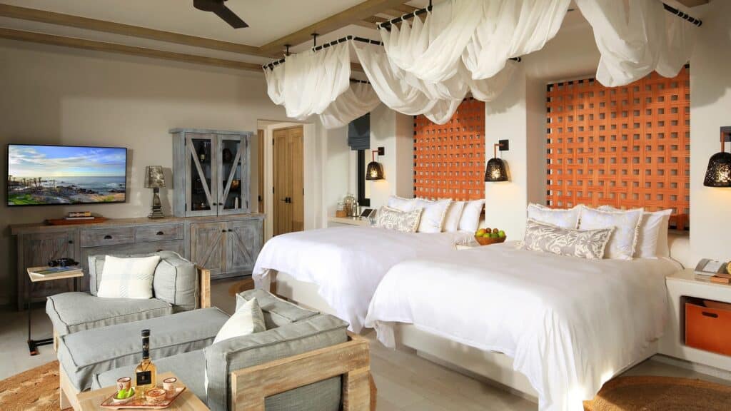 Esperanza, Auberge Collection — guestroom with twin canopied beds, orange headboards and a seating area