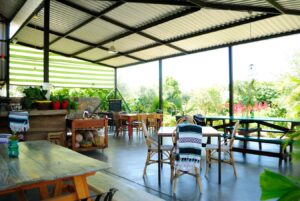 Daytime interior of the open-air palapa dining area with wooden tables, woven chairs and garden views
