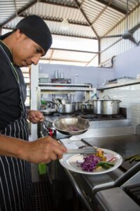 Chef plating a dish at the stove in the open kitchen