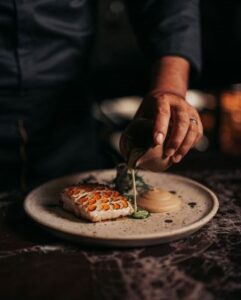 Chef finishing a wood-fired fish dish with citrus at Humo, Zadún a Ritz-Carlton Reserve