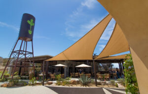 Open-air garden restaurant exterior with the landmark radish-painted water tower and shade sails over the dining area