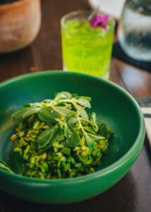 Vivid garden green rice plated in handmade green ceramic with a fresh herb drink