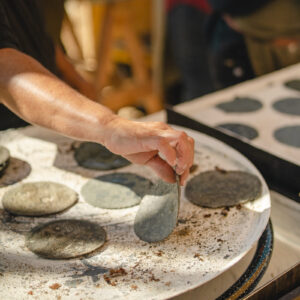 Hands pressing and toasting fresh blue corn tortillas on a comal in the open kitchen