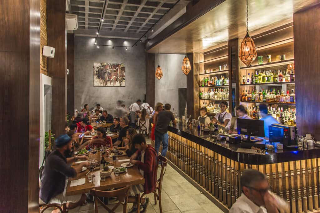 Interior dining room with the long, stocked bar and guests