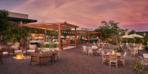 Wide sunset view of Limón: lounge seating and fire pit in the foreground, lit bar and grills under pink sky (official Visit Los Cabos CRM image, 1200x603)