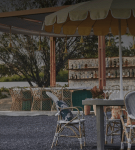 Vertical hero of the umbrella-shaded bar with bottle wall and rattan seating (Onda Cabo official outlet page; tighter crop of the bar scene, 1720x1920)