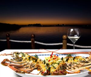 Signature grilled lobster platter with white wine on the marina terrace at sunset at Lorenzillo's