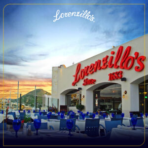 Lorenzillo's Cabo San Lucas exterior and terrace tables at sunset with the marina hillside behind