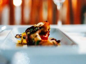 Plated grilled dish photographed with warm candlelight bokeh, evening atmosphere