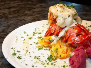 Lobster tail entree with sauce and herbs on a white plate
