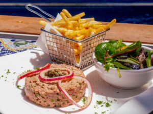 Steak tartare plated with a basket of seasoned fries and a side salad
