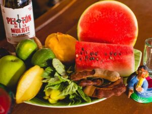 Display of fresh local fruit, herbs, and mezcal highlighting local ingredients