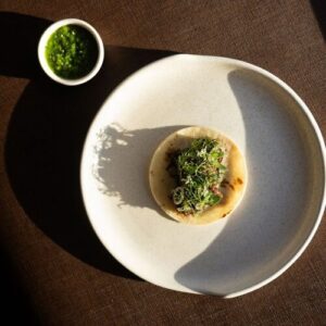 Plated taco course topped with microgreens, served with a small dish of salsa verde (Michelin Guide photo)