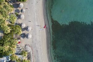 Palapas, kayaks and clear water beside the reef at Playa La Concha, La Paz, from above